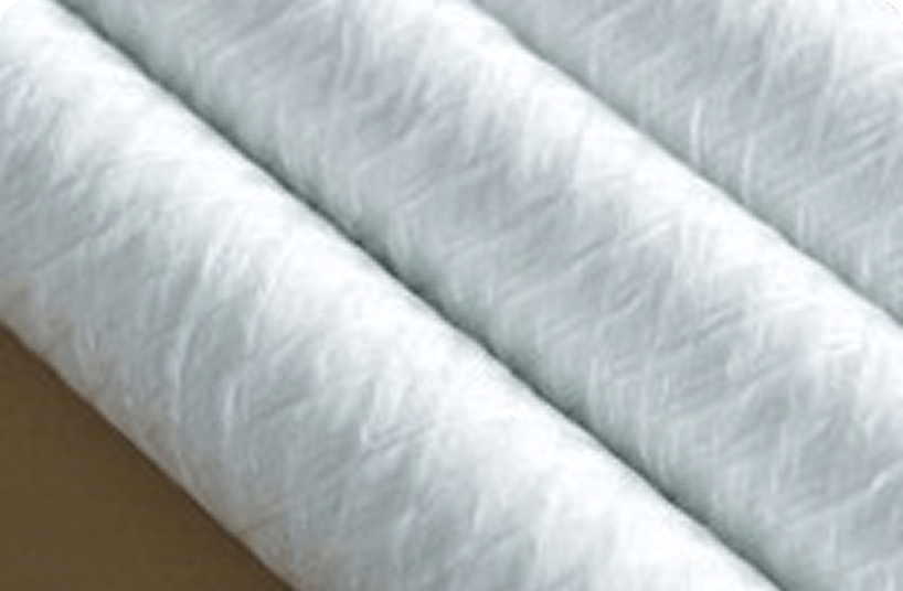 Close-up of white fiberglass filter cartridges with a wound pattern, used in liquid filtration systems.