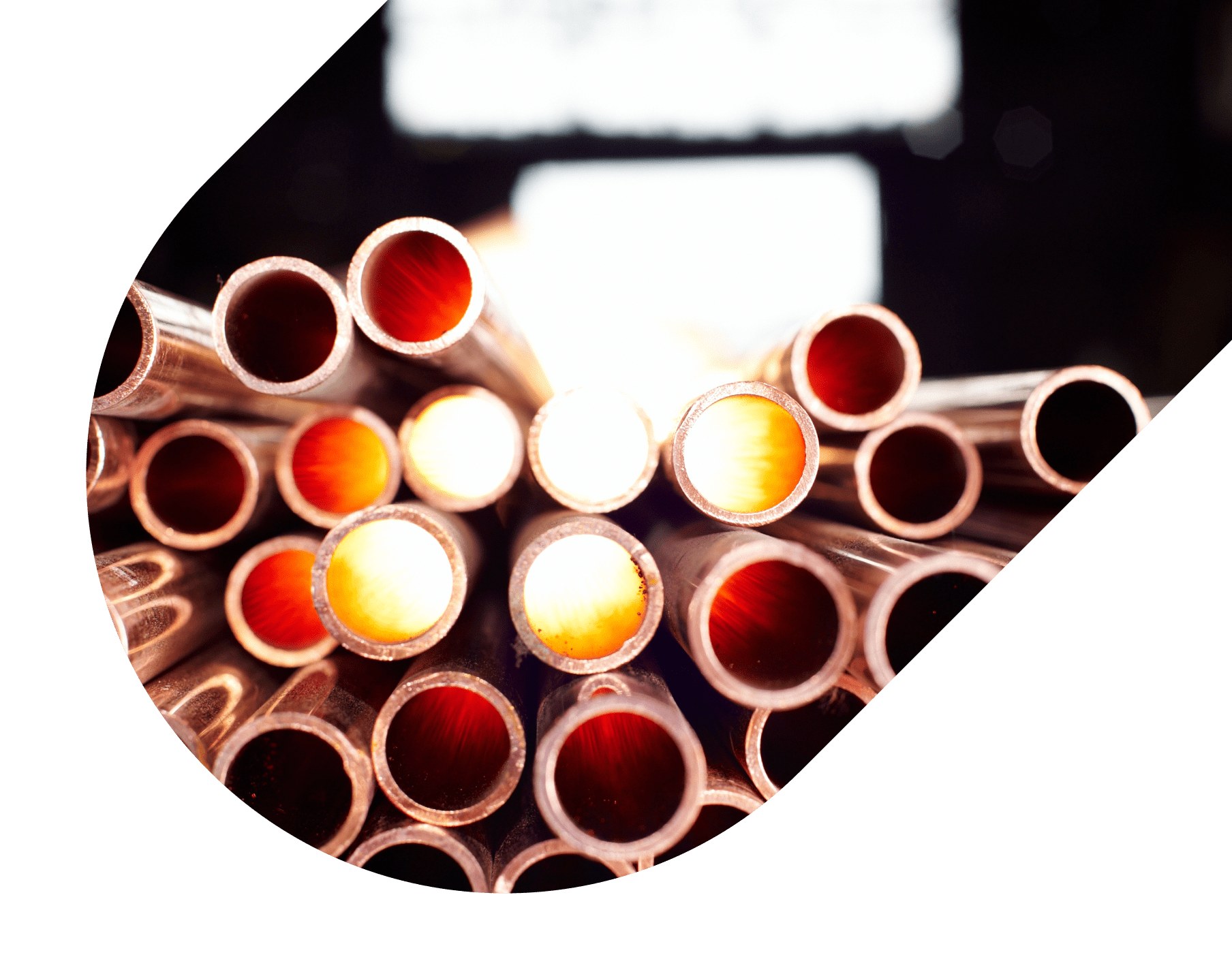 Stacked copper pipes with glowing interiors, viewed from the ends in an industrial setting.