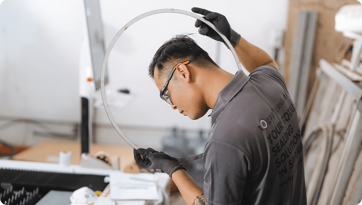 Technician inspecting a circular metal gasket ring for precision and quality in a workshop.