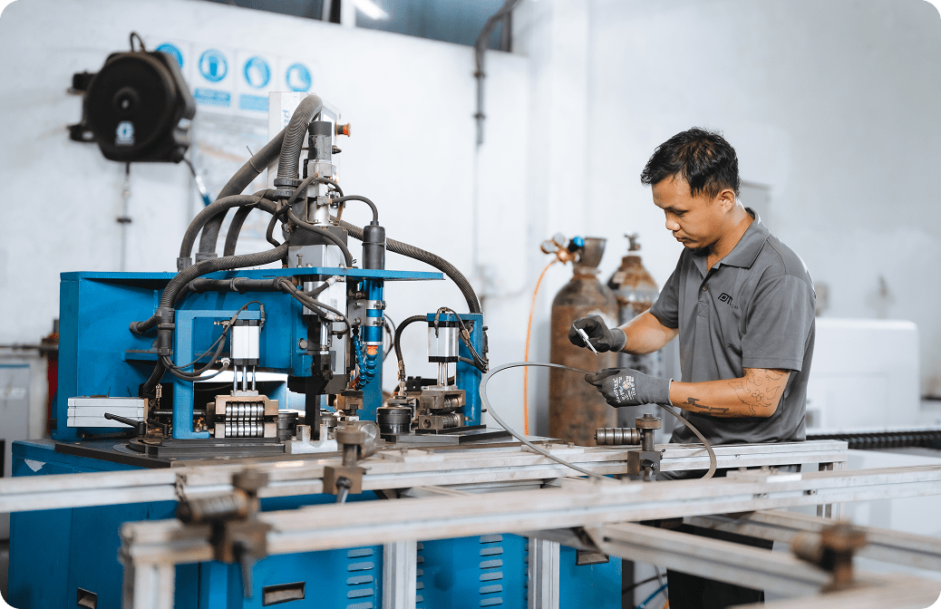 Worker operating hydraulic pipe bending machine in industrial workshop.