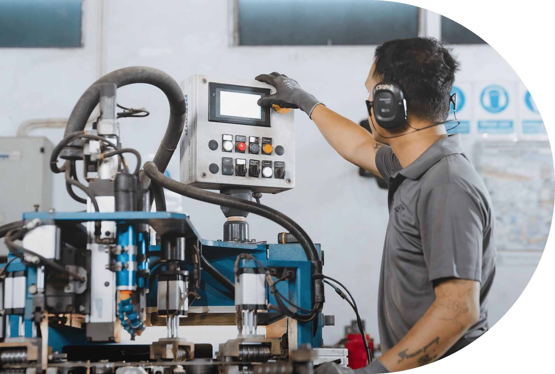 Worker operating CNC machine with touchscreen in industrial setting.