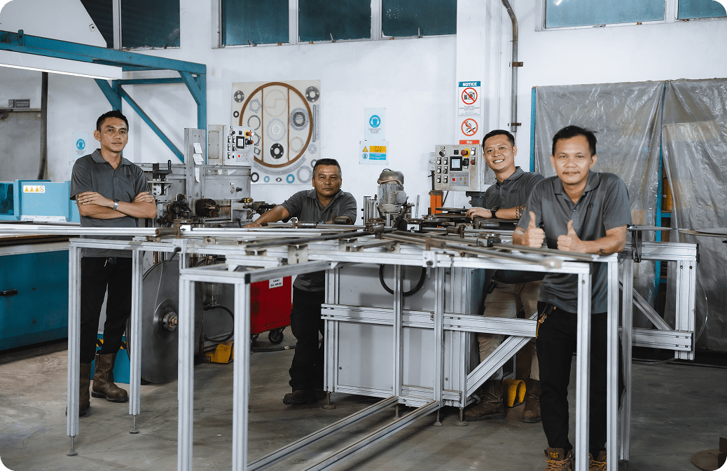 Group of factory workers posing confidently beside industrial bending machinery in a manufacturing workshop.